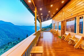A wooden cabin with a balcony overlooking a mountainous landscape. - The Oaknut Cottage Birding Lodge (Kosiyakutoli)