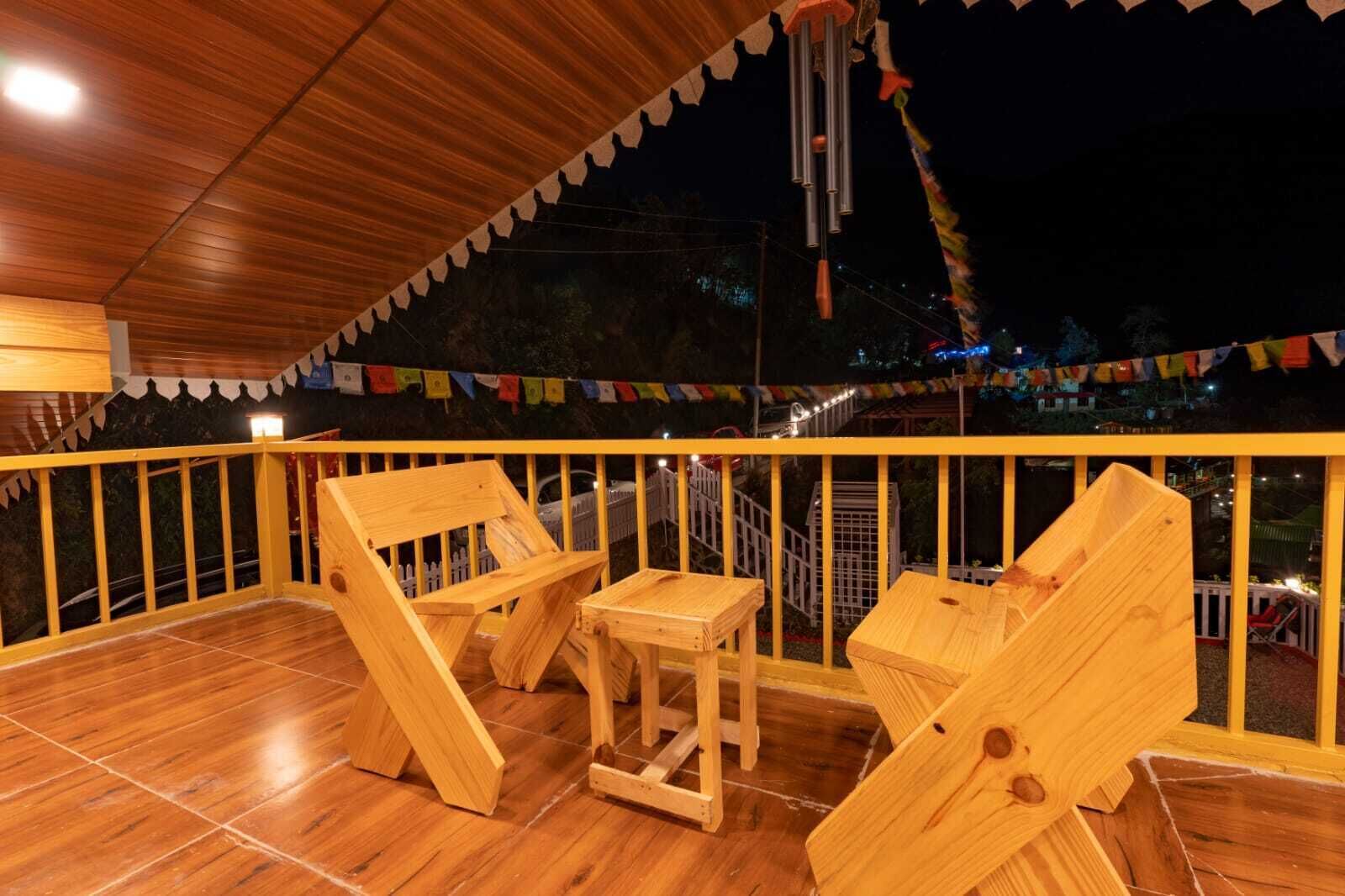 A wooden deck with a railing, two wooden chairs, and a small table.