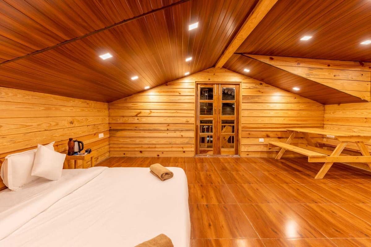 A cozy wooden cabin room with a bed, a table, and a bench.