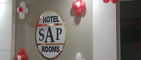 Un letrero en la pared que dice 'HOTEL SAP ROOMS' rodeado de globos rojos y blancos.