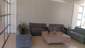 A modern living room with a grey sectional sofa, a wooden coffee table with decorative items, and a grey armchair. - Hotel SAP (Kalol)