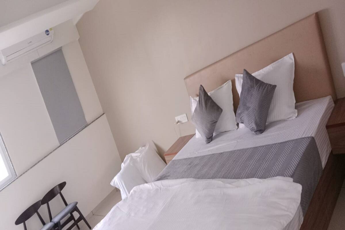 A neatly made bed with white and gray bedding, a wooden headboard, and a small bedside table.