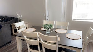 A dining area with a dark wooden table, white chairs, and woven placemats.