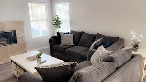 A modern living room with a grey sofa set, a white coffee table, and a small potted plant.