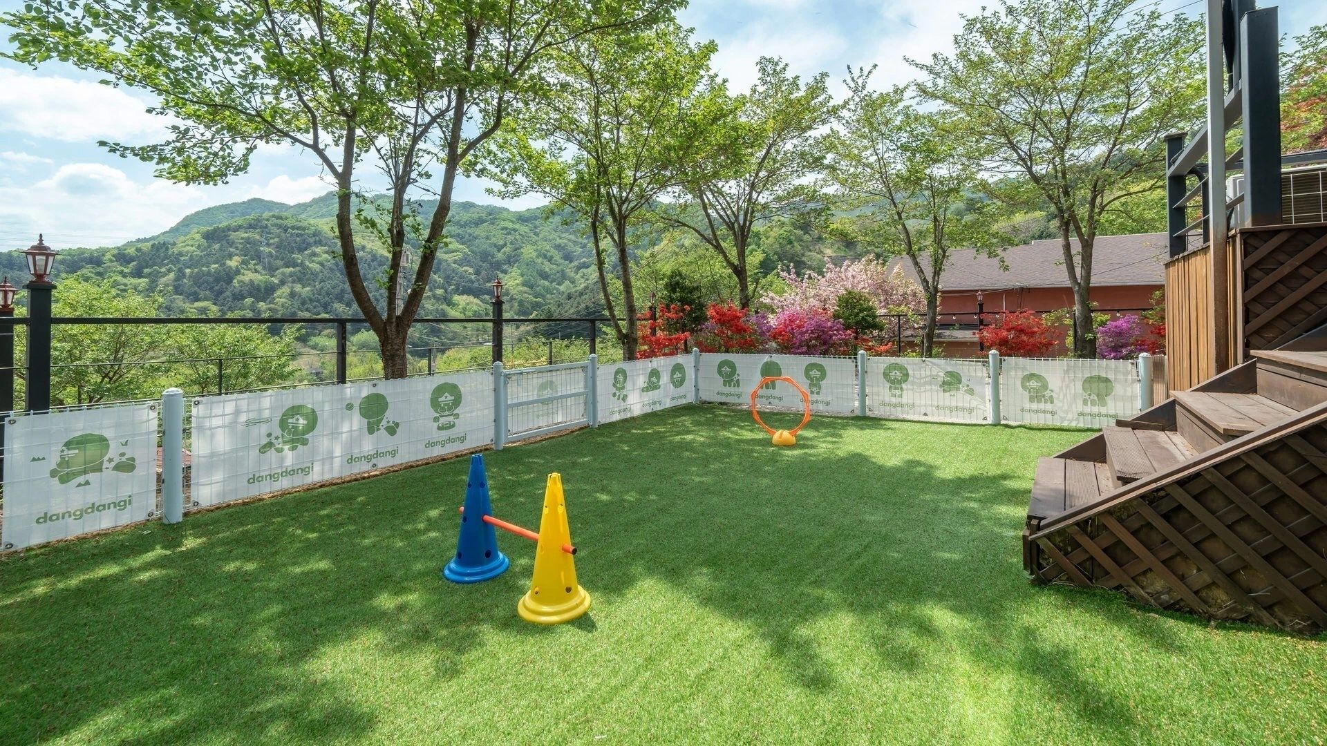 Un espacio al aire libre con césped, una estructura de juego de madera, una cerca y árboles.