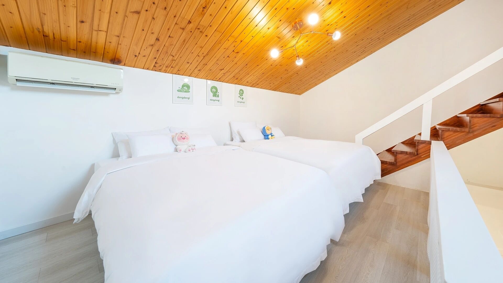 A bedroom with two beds, a wooden ceiling, a staircase, and an air conditioning unit.