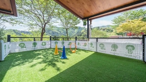 An outdoor area with artificial grass, a wooden pergola, and a view of a forested landscape. - Gapyeong Daengdaengi Dog Pension Silver (Gapyeong)