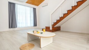 Un intérieur moderne avec un escalier, une table à manger et une grande fenêtre agrémentée de rideaux.
