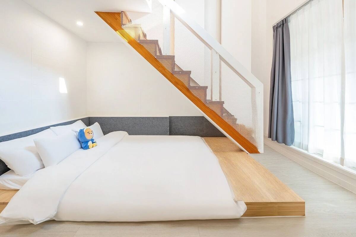 Une chambre moderne avec un lit intégré, un escalier en bois et de grandes fenêtres.
