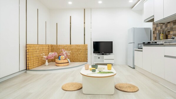 Eine moderne Küche mit eingebautem Herd, weißen Schränken und einem Fernseher auf einem weißen Schrank.