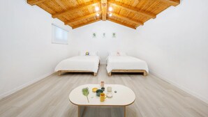Een kamer met twee bedden, een tafel met bekers en een plant, en een houten plafond.