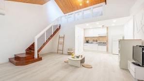 A spacious living area with a wooden staircase, a kitchen, and a television. - Gapyeong Daengdaengi Dog Pension Silver (Gapyeong)
