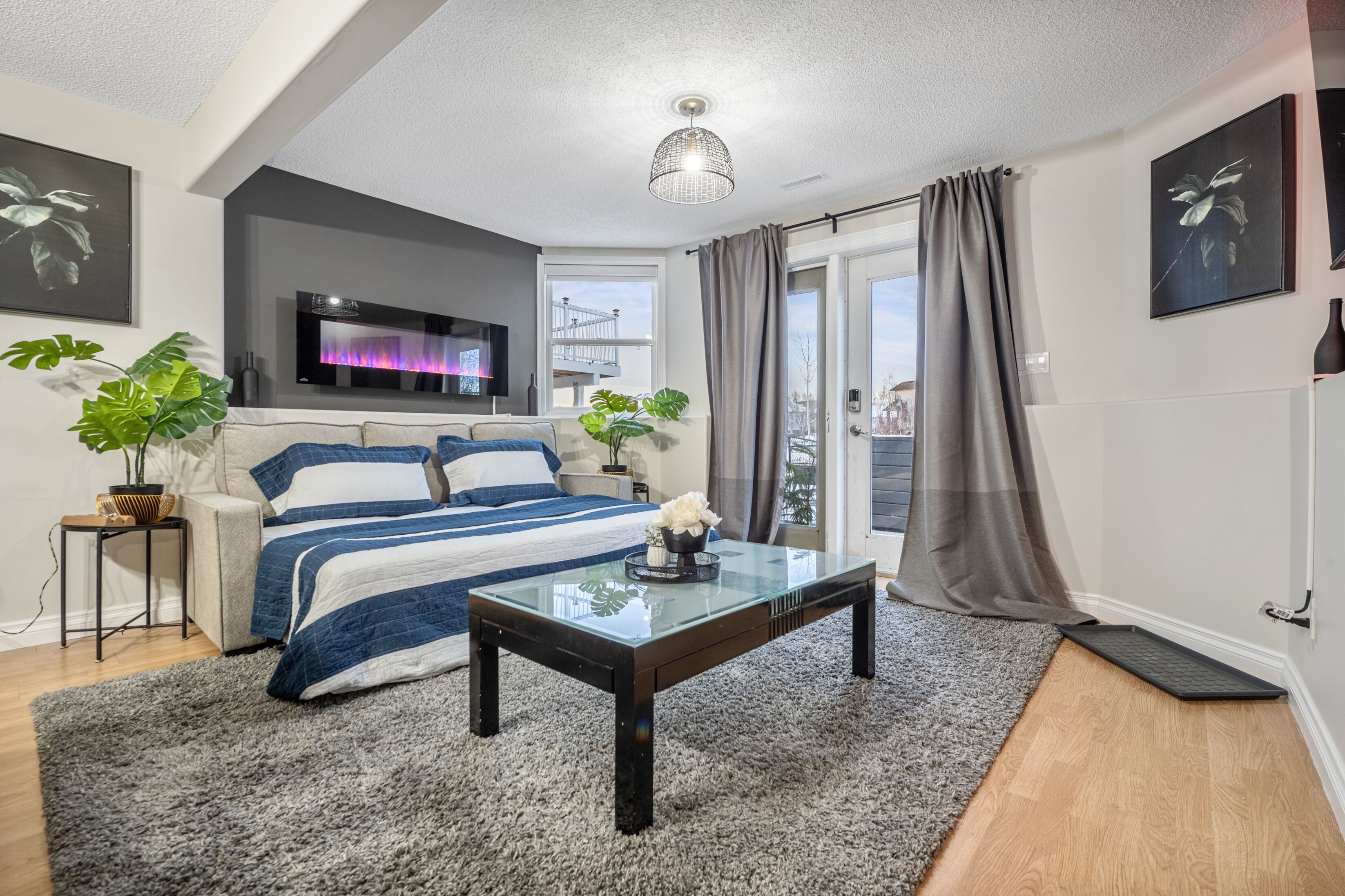 A modern bedroom with a bed, a glass coffee table, a TV, and a view of the outside.