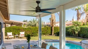 A covered patio with a pool, outdoor furniture, and a view of the surrounding landscape.