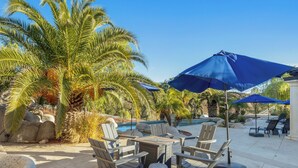 A poolside area with lounge chairs, a table, and umbrellas. - Expansive Wine Country Estate | Pool + Hot Tub | Sleeps 20 | Quiet Retreat (Temecula)