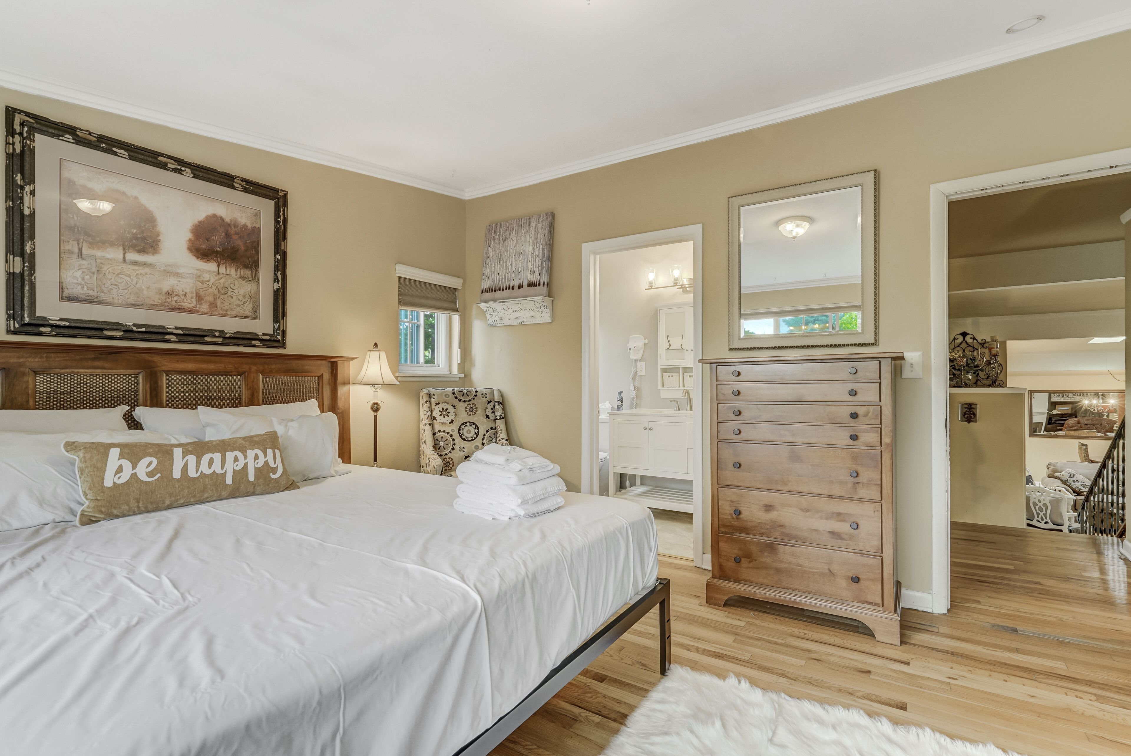 A bedroom with a bed, a dresser, a mirror, and a painting on the wall.