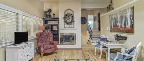 A living room with a fireplace, a television, and a chess table.