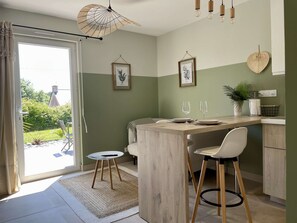 Una cocina moderna con una isla central, taburetes de bar y una mesa de comedor.