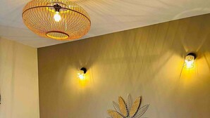 Et soveværelse med en seng, to vægmonterede lamper, blad-vægkunst og en loftlampe.