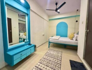 A bedroom with a large mirror, a bed with a blue headboard, a bedside table, and a patterned rug.