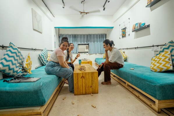 A small, cozy room with two teal sofas, a wooden coffee table, and a small wooden bed.