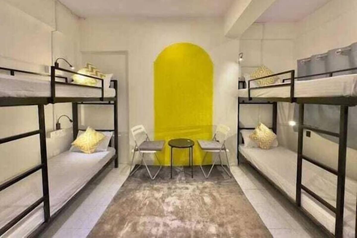 A dormitory room with bunk beds, a small table, and chairs.