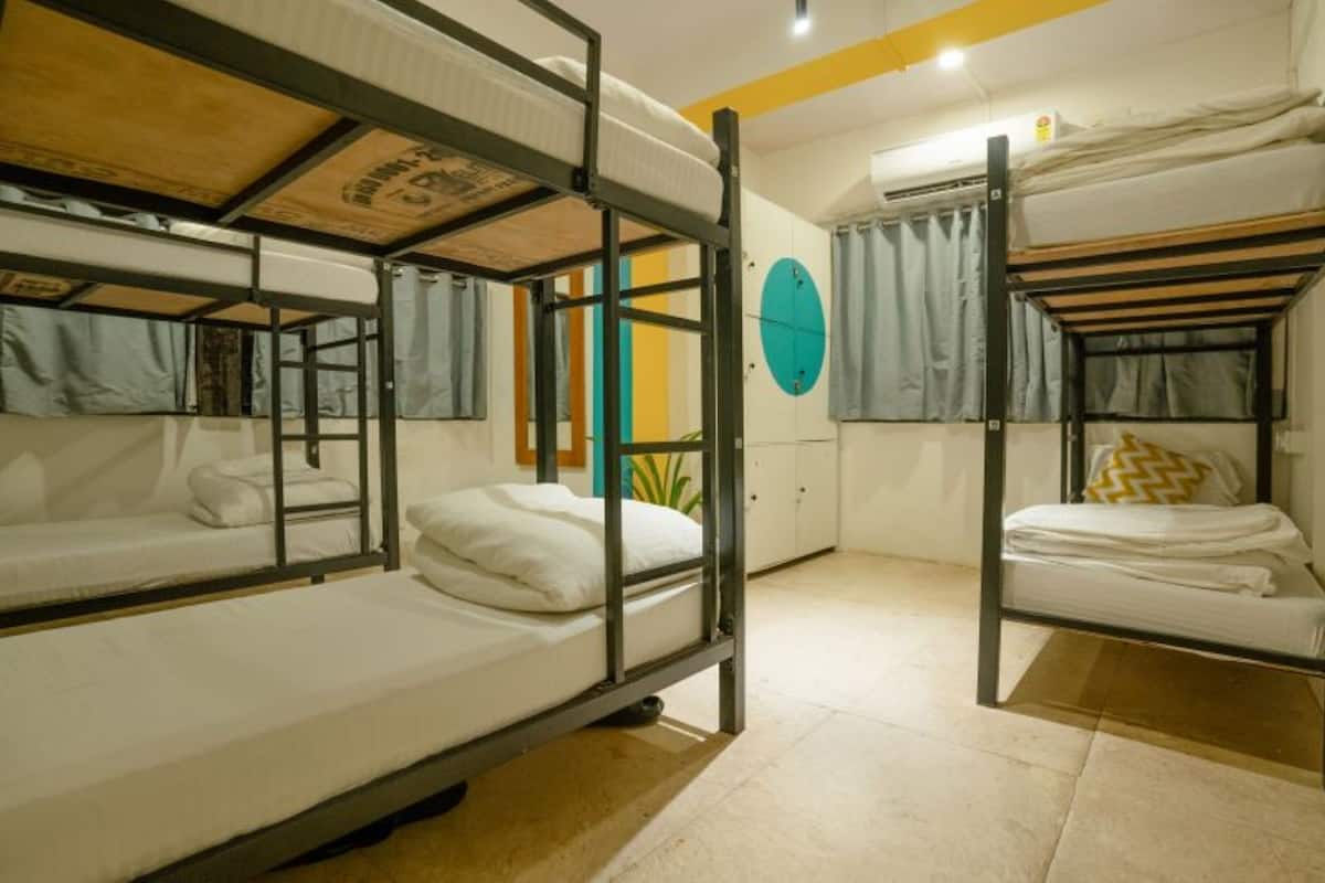A dormitory room with bunk beds, a window with curtains, and a circular wall decoration.