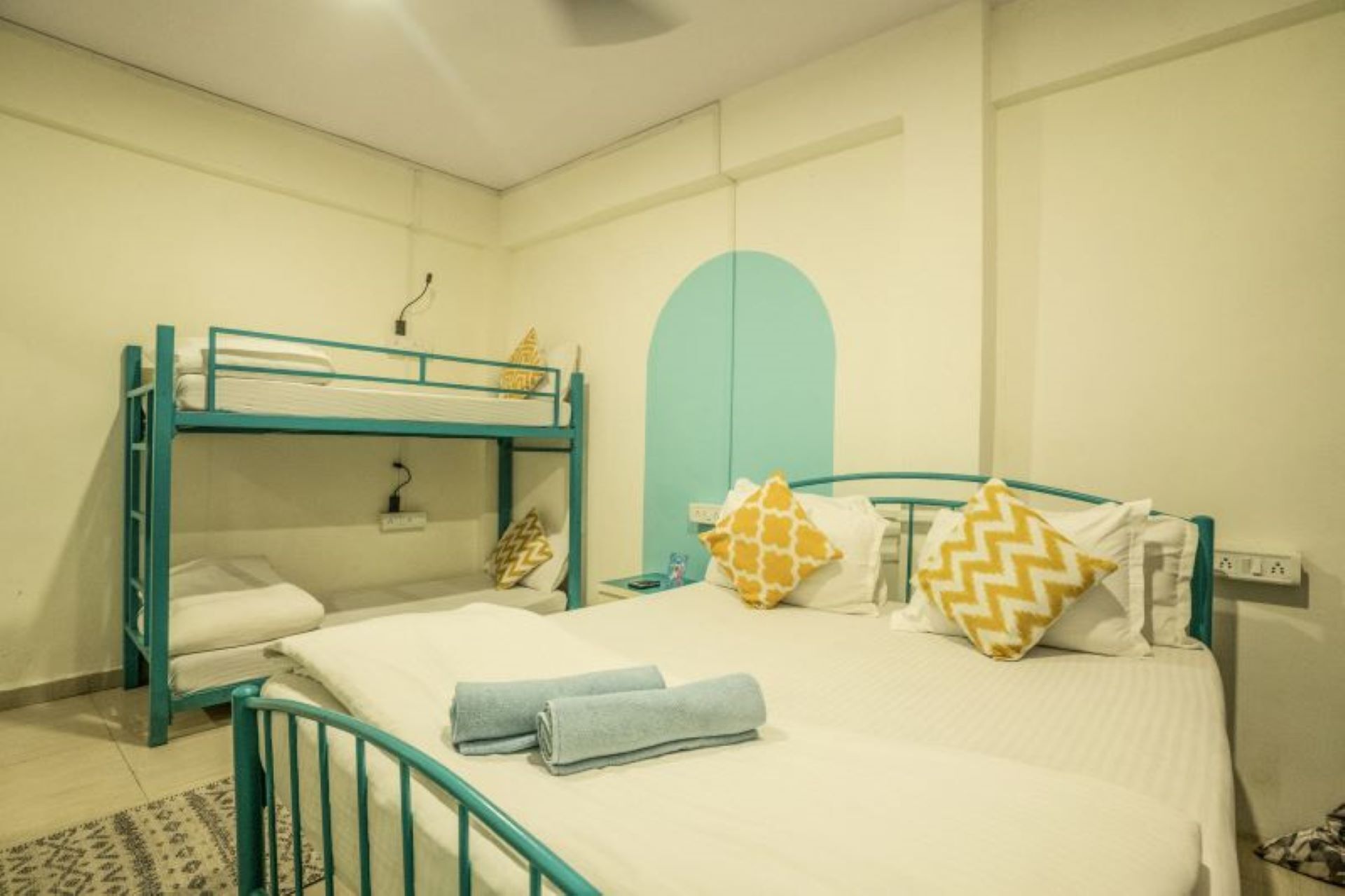 Una stanza con un letto a castello, un letto singolo e una piccola scrivania.