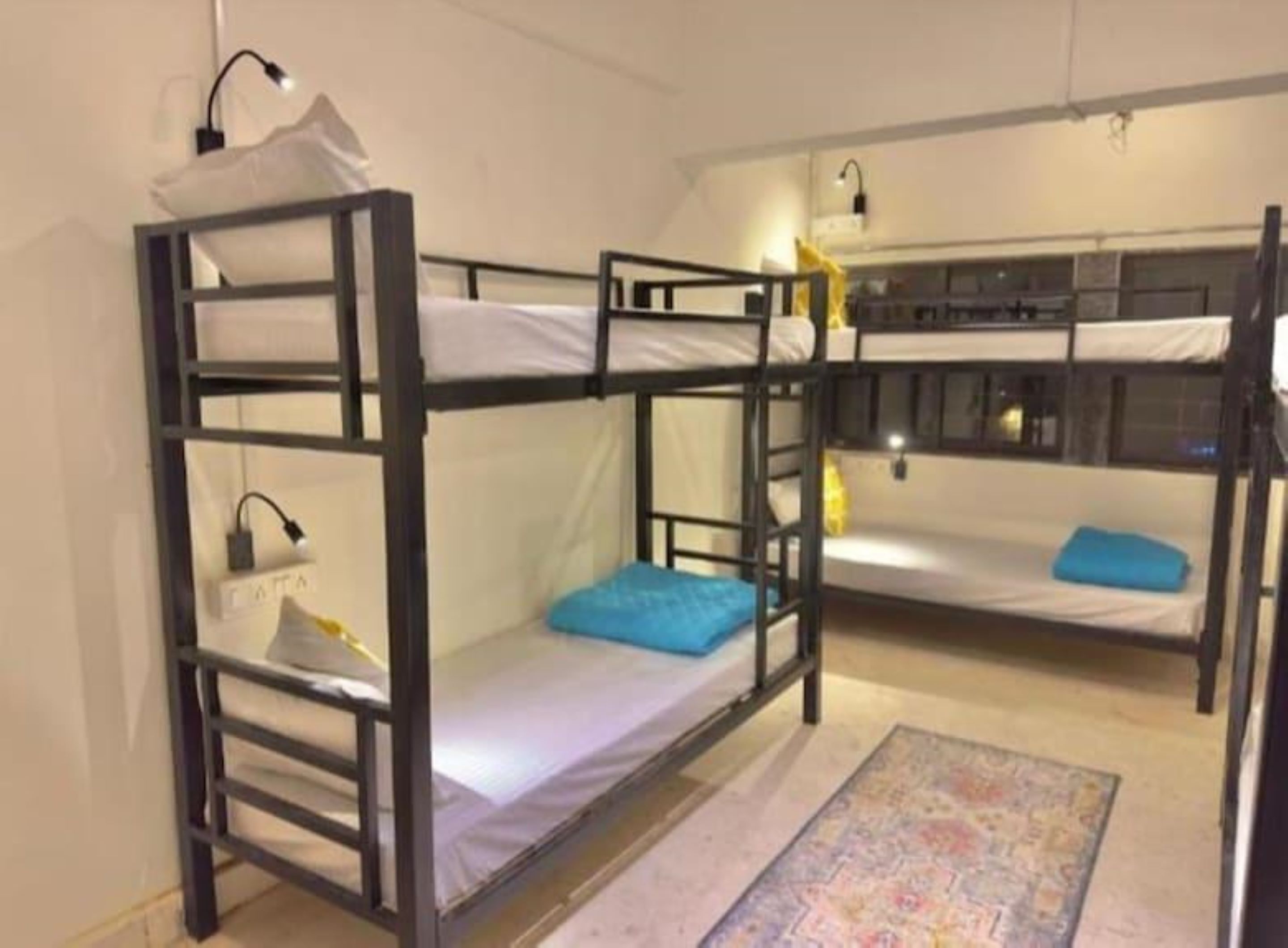 A bunk bed room with two beds, a small rug, and a nightstand with a lamp.