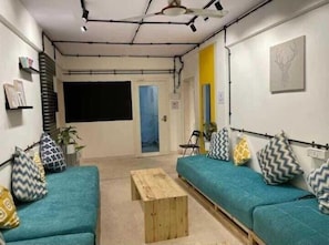 A modern living room with teal sofas, a wooden coffee table, and patterned cushions.