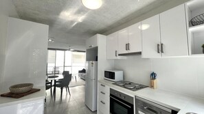 Una cocina moderna con gabinetes blancos, un refrigerador, un microondas y una estufa.