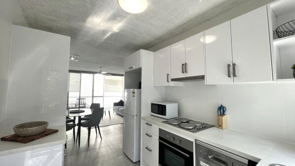 A modern kitchen with white cabinets, a refrigerator, a microwave, and a stove.