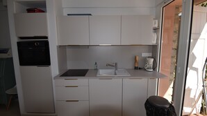 A compact kitchen with a built-in oven, a sink, and a coffee maker. - PRESQU'Île de GIENS STUDIO REZ-de-JARDIN villa Parc Résidentiel la POLYNESIE (Hyères)