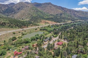 Un paisaje montañoso con una carretera, un lago y varias casas con tejados rojos.