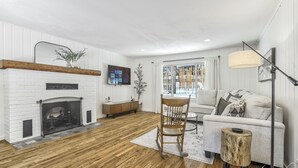 A living room with a fireplace, a sofa, a coffee table, and a side table. - Green Dream (Cascade)