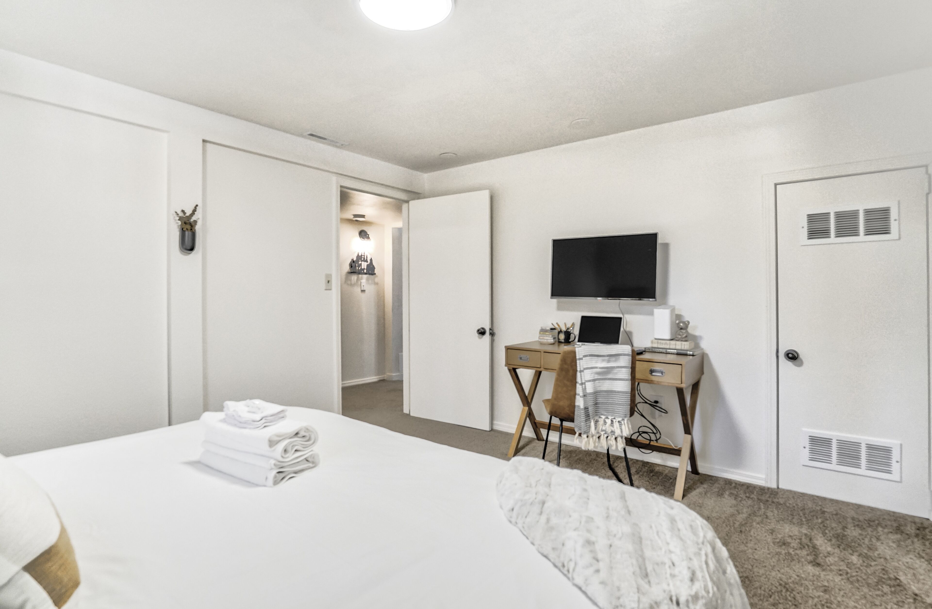 Hotellihuone, jossa on sänky, työpöytä tietokoneella, televisio ja vaatekaappi.