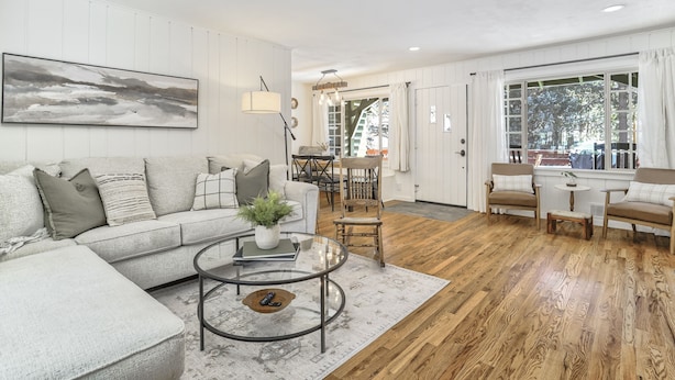 A modern living room with a sectional sofa, a glass coffee table, and a wooden floor. - Green Dream (Cascade)