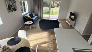 Un salon moderne comprenant un canapé, un téléviseur et un coin repas avec une table et des chaises.