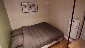 A small, single-bed room with a wooden floor, a white radiator, and a framed picture on the wall. - Chalet - Terrasse & bain nordique (Trégastel)