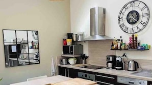 Una cocina moderna con una isla central, electrodomésticos de acero inoxidable y un reloj de pared grande.