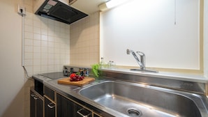Una cocina con un lavamanos de acero inoxidable, un microondas y una tabla de cortar de madera con uvas.