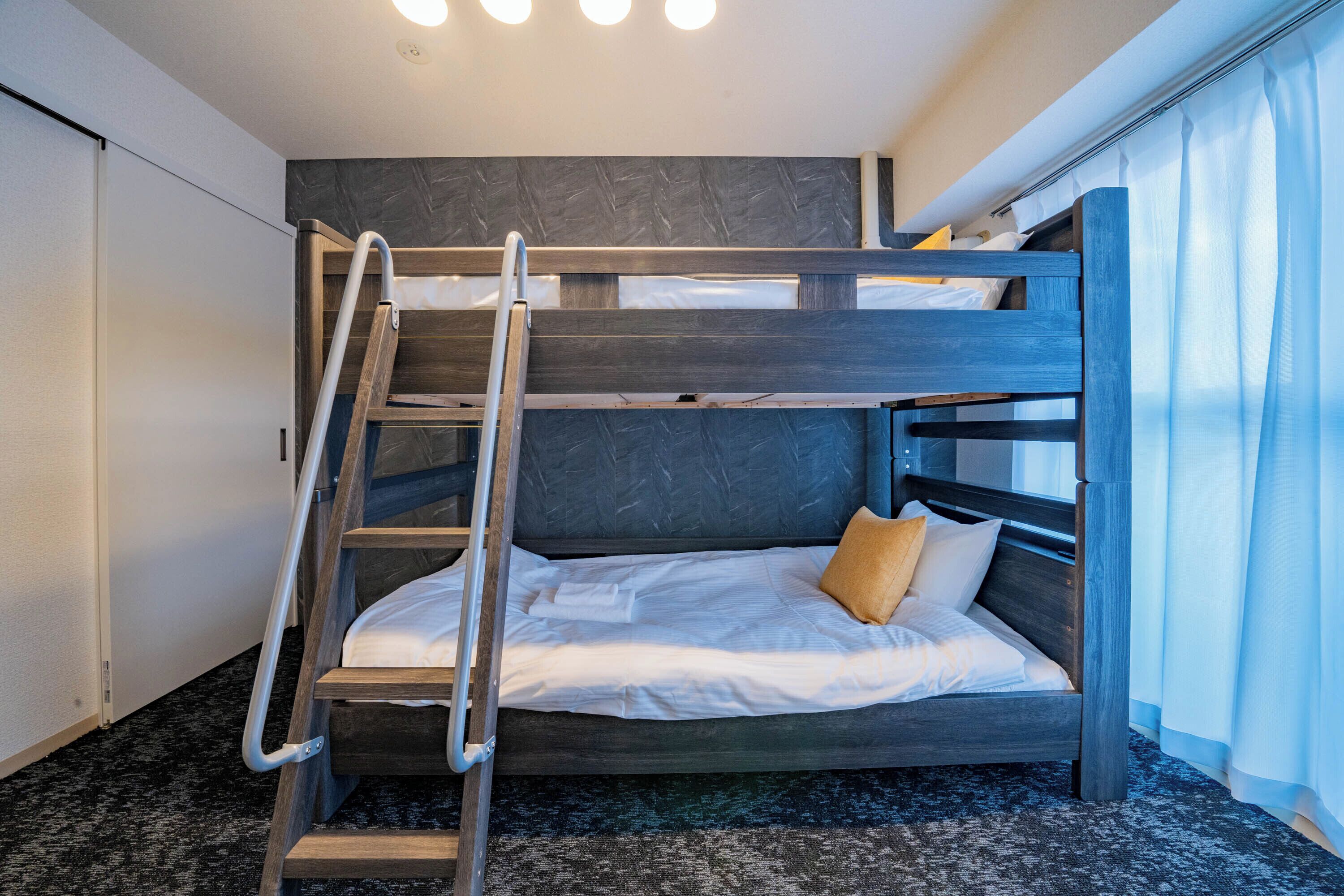 A bunk bed with a ladder, white bedding, and a brown pillow.