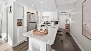 Une cuisine moderne avec des meubles blancs, un îlot central et un plateau en bois.