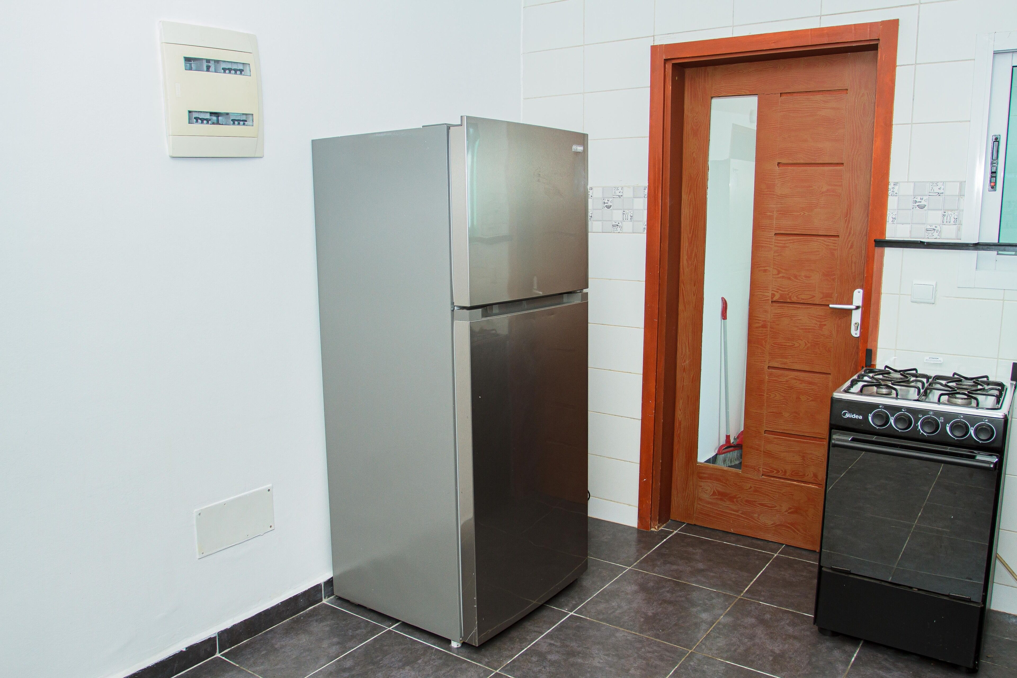 A kitchen with a stainless steel refrigerator, a gas stove, and a wooden door.