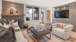 Een moderne woonkamer met een open haard, een bank, een salontafel en een televisie.