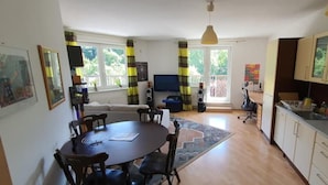 Amplia sala de estar con una mesa de comedor, sillas, un sofá y una zona de cocina con armarios y estufa.