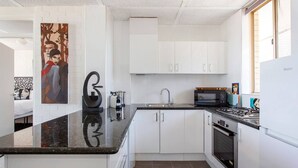 A modern kitchen with white cabinets, a black countertop, a microwave, and a stove.