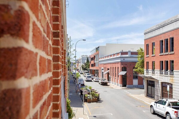 A street view with brick buildings, parked cars, and a clear sky.