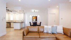 Un salon moderne avec un canapé en cuir, une table à manger et une cuisine en arrière-plan.