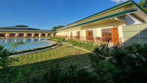 Un hotel con piscina, mobiliario exterior y una zona cubierta.